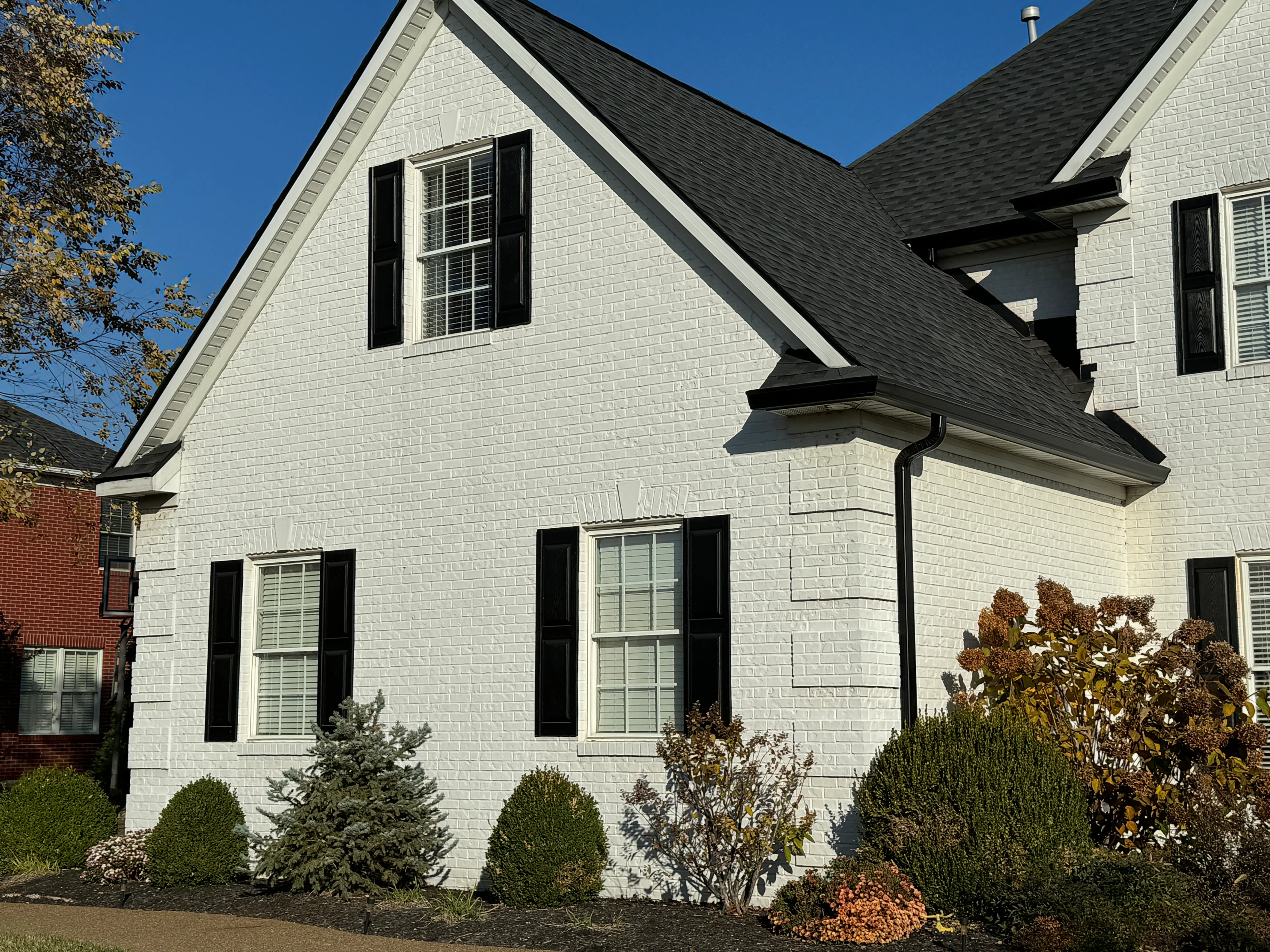 Finished black seamless gutters on a white brick home