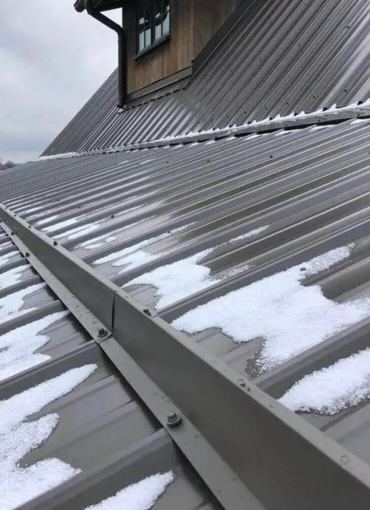 Snow and winter runoff along a metal roof and gutter system